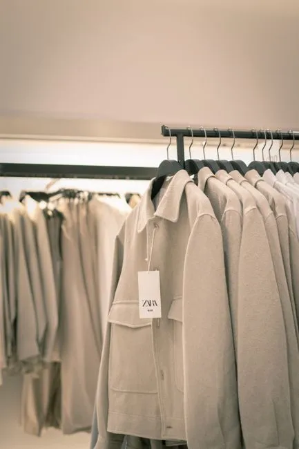 Manteaux beiges alignés sur des portants dans une boutique de prêt-à-porter